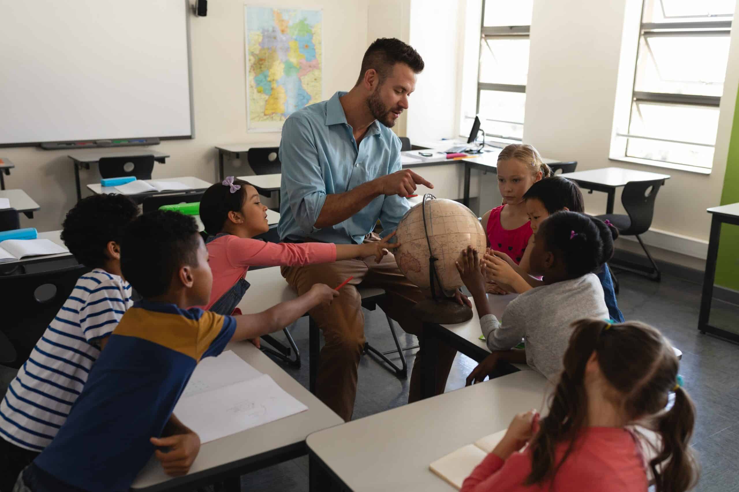 teacher and students in the classroom looking at a globe